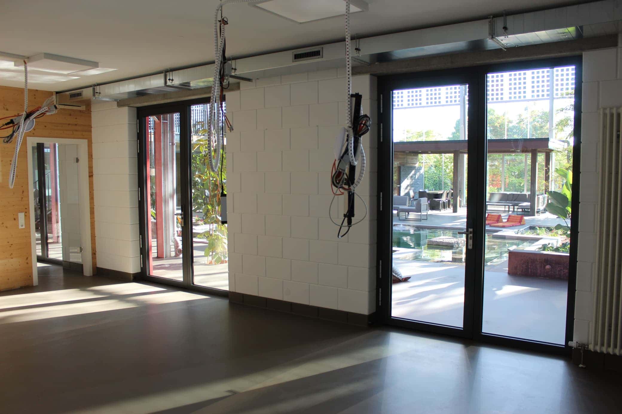 Heller Raum mit Glastüren und Blick ins Atrium mit Wasserbecken und Pavillon